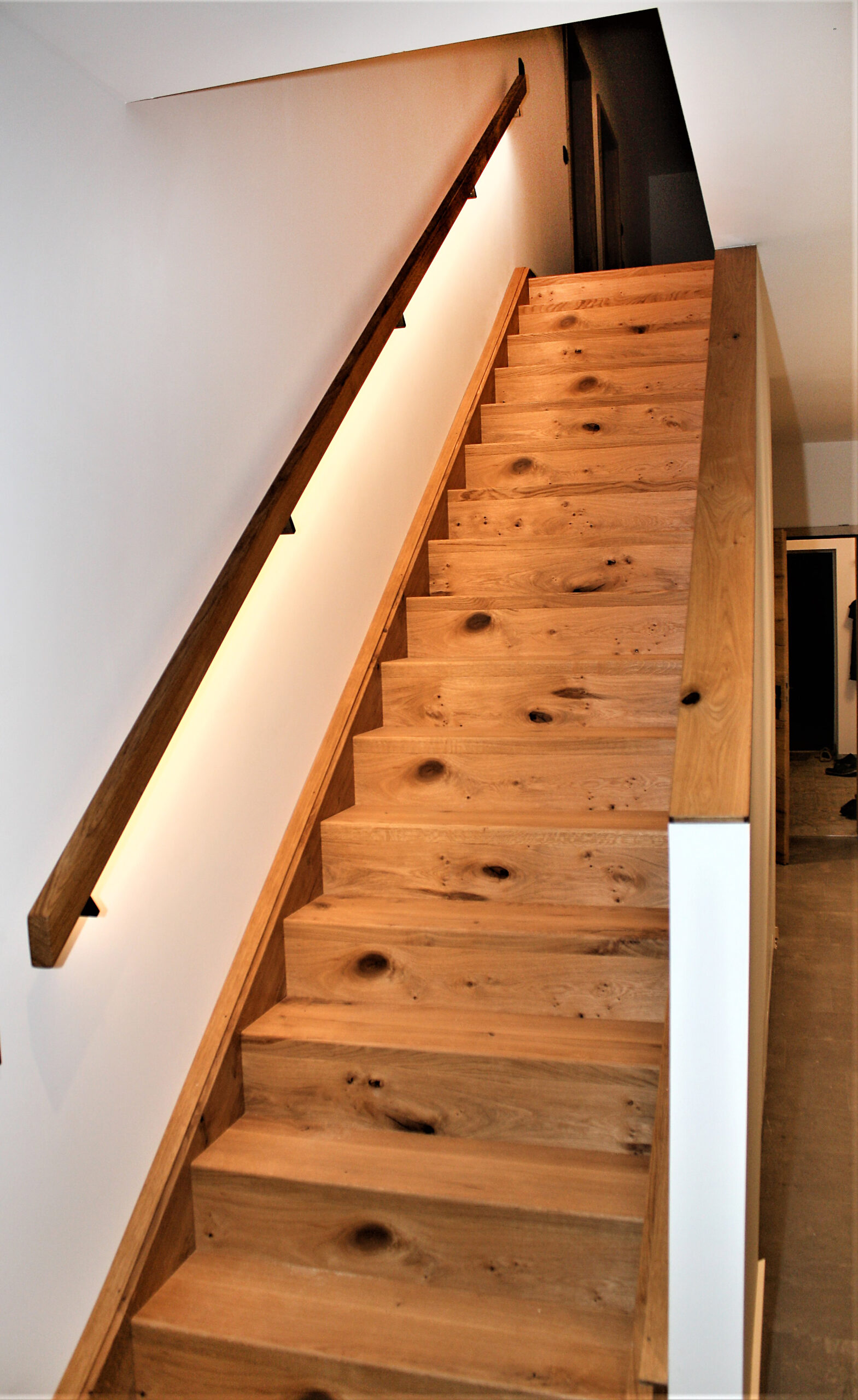 Holztreppe mit Geländer und indirekter Beleuchtung
